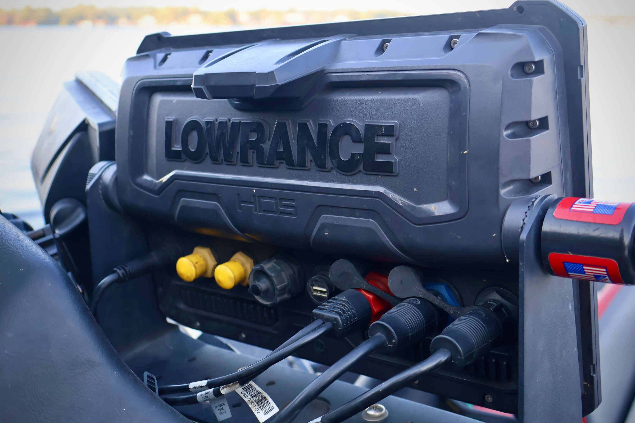 Lowrance device with various cables connected, used for marine navigation and fish finding on a boat.