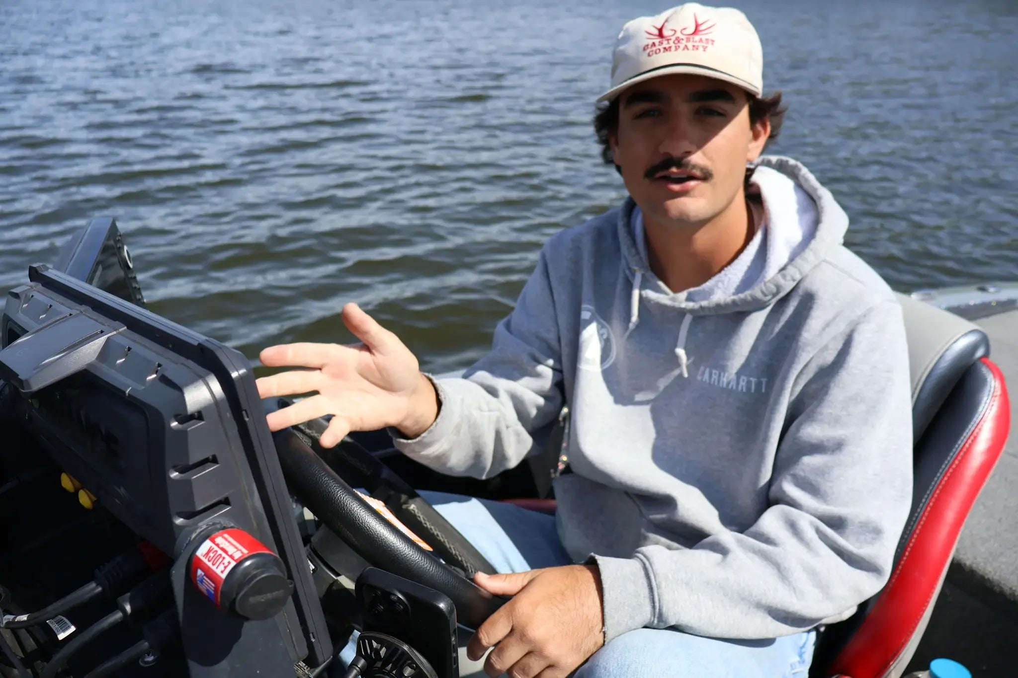 Angler talking to the camera while gesturing toward fishfinders. 