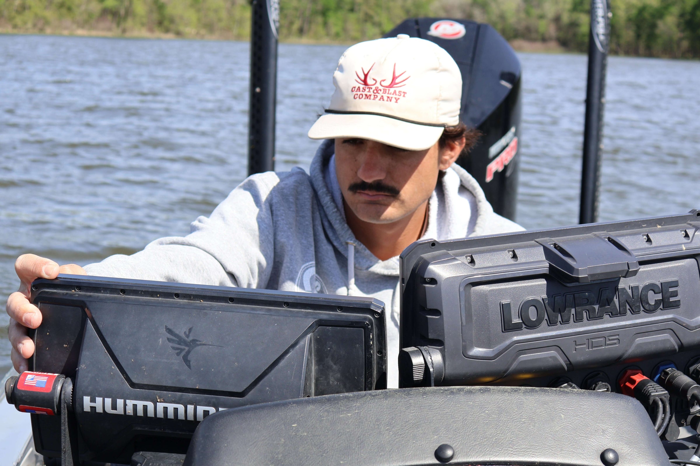 Angler using fish finder equipment on a boat during a fishing trip on a lake.