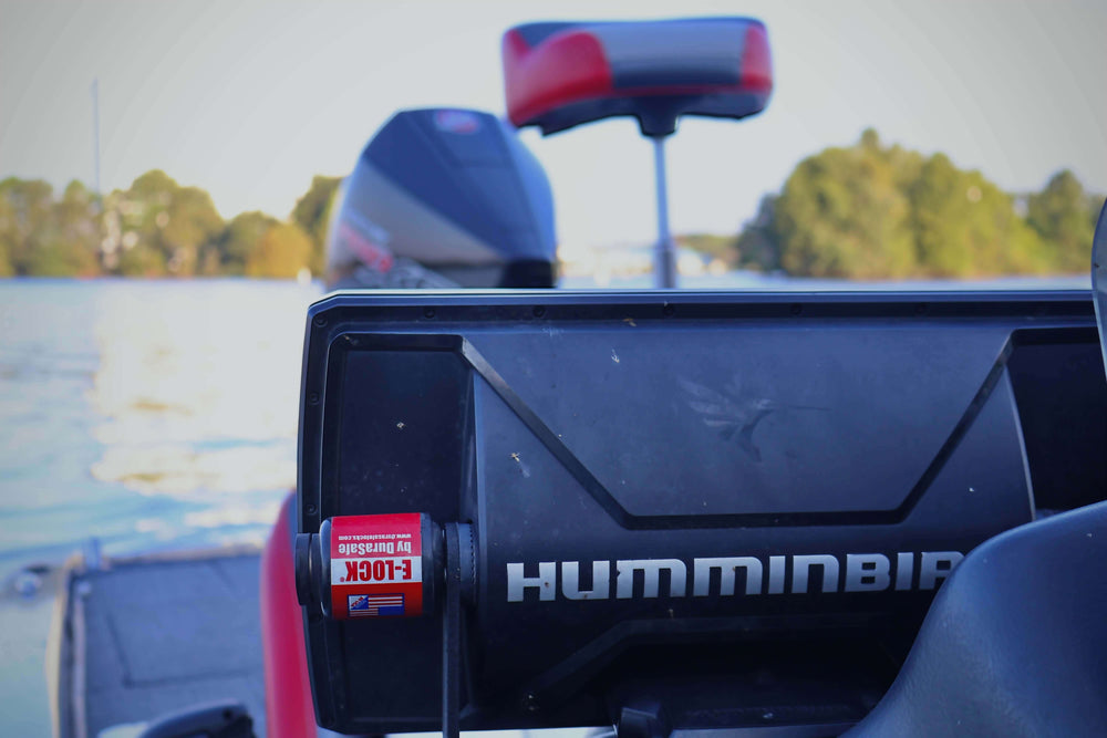 Humminbird fish finder on a boat with a scenic lake background.