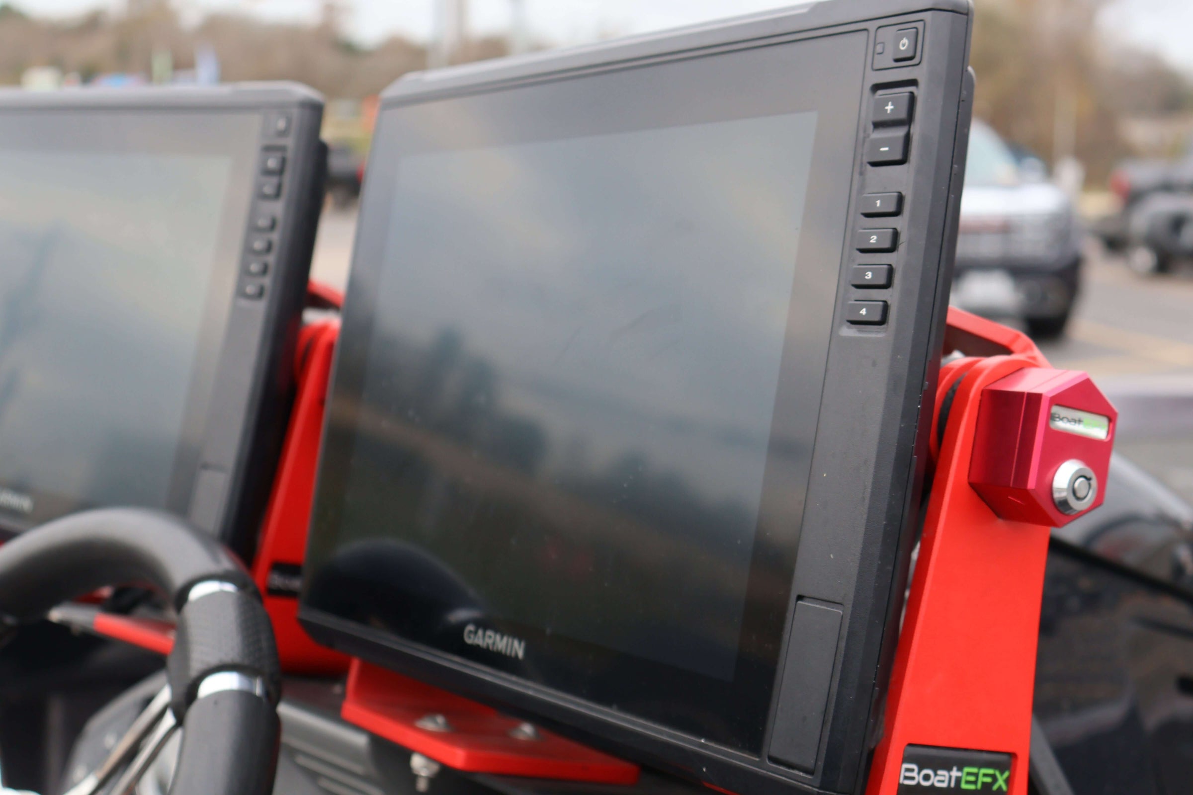 Close-up of a Garmin marine GPS device mounted on a red support in a vehicle.