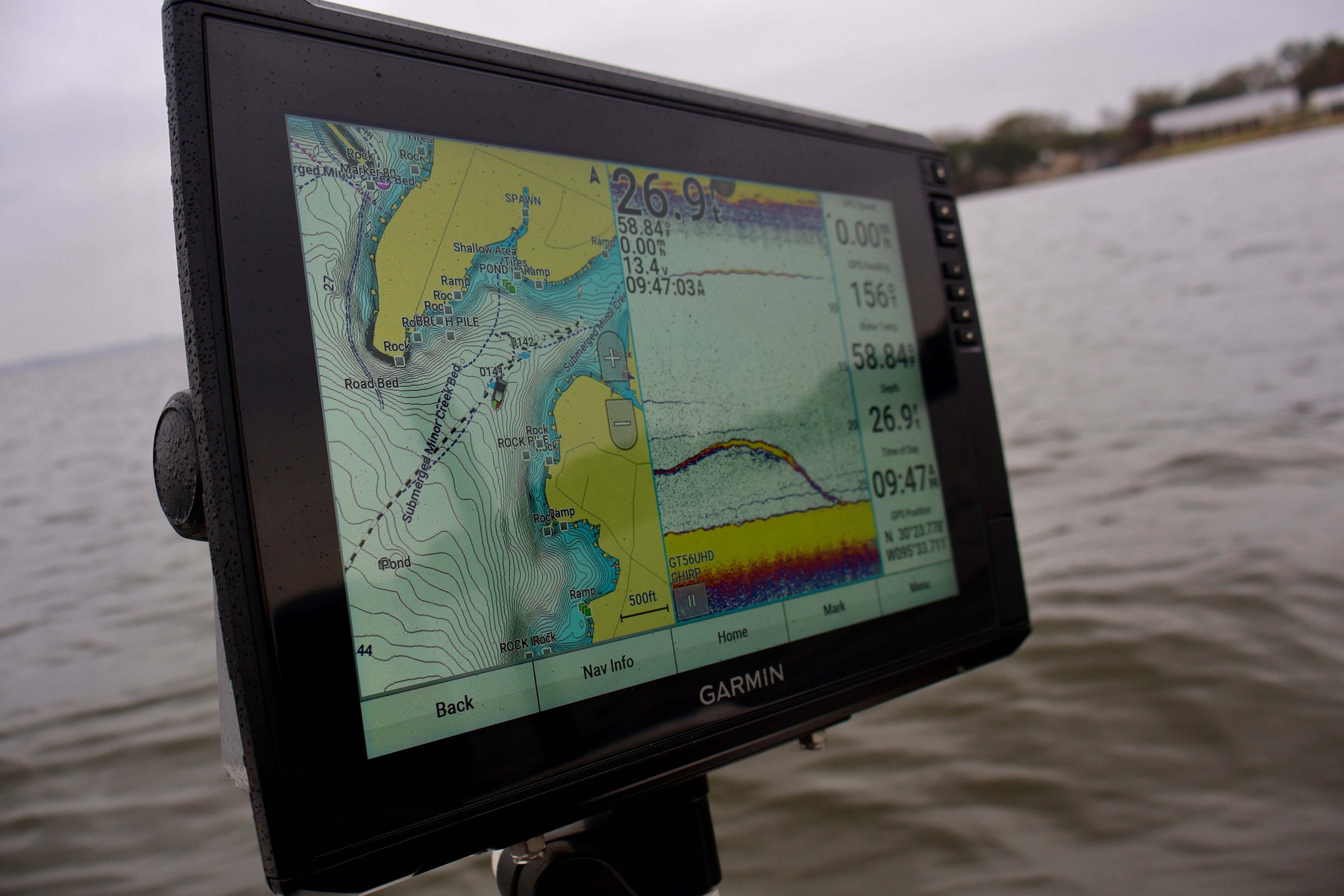 Fishfinder sonar display on a boat showing water depth, map, and fish activity in a lake setting.